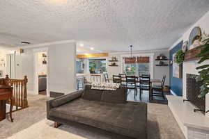 Living room featuring ornamental molding, carpet floors, a chandelier, and a textured ceiling