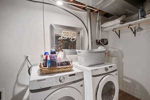 Clothes washing area with hardwood / wood-style flooring and washer and dryer