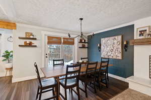 Dining room with wood-type flooring, ornamental molding, and a textured ceiling