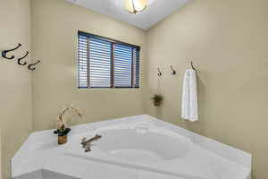 Bathroom featuring a textured ceiling and a tub