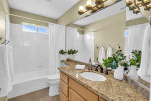 Full bathroom featuring toilet, tile patterned floors, shower / bathtub combination with curtain, and vanity