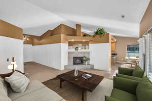 Living room with vaulted ceiling, an inviting chandelier, and a fireplace