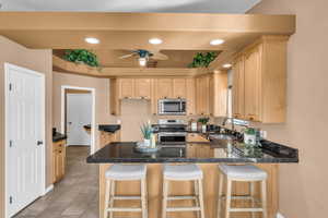 Kitchen featuring sink, light brown cabinets, kitchen peninsula, and appliances with stainless steel finishes