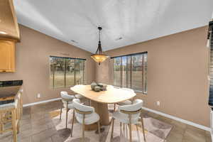 Tiled dining room with lofted ceiling and a textured ceiling