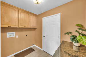 Laundry area featuring light tile patterned floors, electric dryer hookup, cabinets, washer hookup, and a textured ceiling