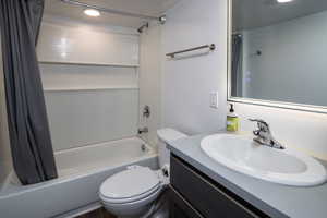 Full bathroom with vanity, toilet, and shower / bathtub combination with curtain