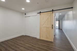 Unfurnished bedroom featuring dark hardwood / wood-style flooring, a closet, and a barn door