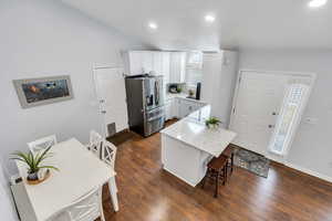 Kitchen featuring stainless steel appliances, a breakfast bar, white cabinetry,  wood-style floors, built in microwave, and a kitchen island