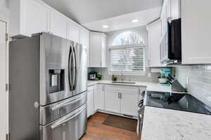 Kitchen featuring sink, white cabinetry, quartz counters, appliances with stainless steel finishes, and  wood-style floors