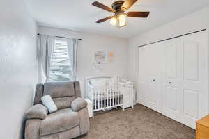 Bedroom featuring a closet, a nursery area, ceiling fan, and carpet