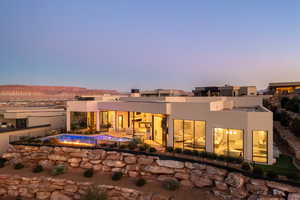 Back house at dusk with a fenced in pool, a mountain view, and a patio