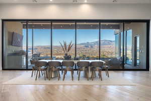 Dining area with a mountain view, light hardwood / wood-style flooring, a wall of windows, and plenty of natural light