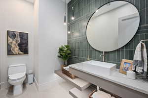 Bathroom featuring tile patterned flooring, sink, tile walls, and toilet