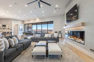 Living room with a high ceiling, light hardwood / wood-style floors, ceiling fan, and a multi sided fireplace