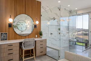 Bathroom featuring a shower with door, vanity, and a wealth of natural light