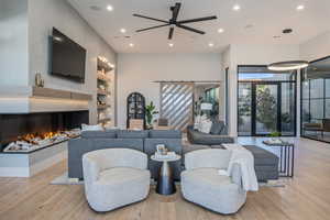 Living room featuring a multi sided fireplace, light hardwood / wood-style flooring, and built in shelves