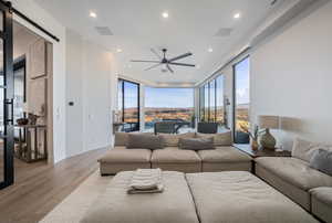 Living room featuring ceiling fan, floor to ceiling windows, a barn door, and light hardwood / wood-style floors