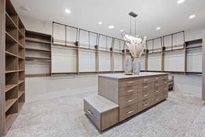 Walk in closet featuring an inviting chandelier and light carpet