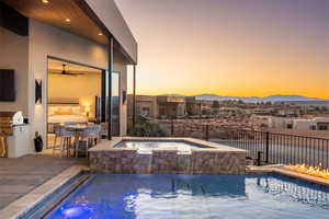 Pool at dusk featuring a patio, area for grilling, an in ground hot tub, ceiling fan, and a mountain view