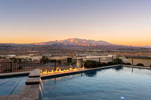 Pool at dusk with a mountain view and pool water feature