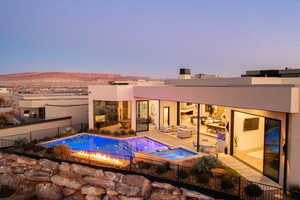 Pool at dusk featuring an in ground hot tub, a mountain view, an outdoor hangout area, and a patio area