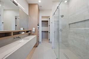 Bathroom with tile patterned flooring, vanity, and a shower with door