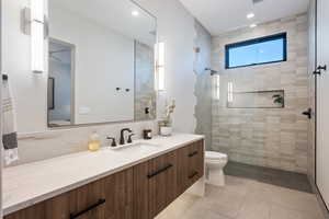 Bathroom with vanity, toilet, a shower with shower door, and tile patterned flooring