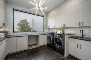 Laundry room featuring cabinets, sink, an inviting chandelier, and washer and clothes dryer