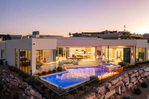 Pool at dusk featuring an in ground hot tub and a patio area