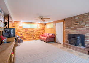 Living room with wooden walls, ceiling fan, and a wood stove