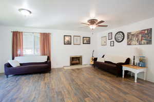 Living room featuring dark wood-type flooring and ceiling fan