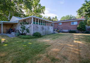 Back of property with a yard and a sunroom