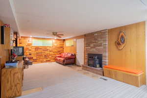 Living room featuring ceiling fan, wood walls, and a wood stove