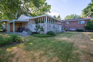 Rear view of house featuring a sunroom and a lawn