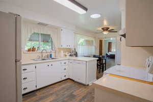 Kitchen with sink, white appliances, white cabinetry, dark hardwood / wood-style floors, and kitchen peninsula