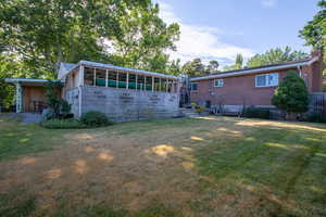 Rear view of house with a yard and a sunroom