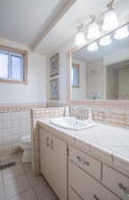 Bathroom featuring vanity, toilet, tile patterned flooring, and tile walls