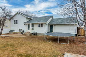 Back of house featuring a patio, a lawn, a trampoline, and central air condition unit