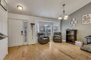 Entryway with a notable chandelier, vaulted ceiling, and light wood-type flooring