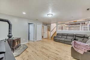 Living room featuring a wood stove, a textured ceiling, and light wood-type flooring