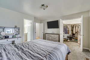 Bedroom featuring a walk in closet, light colored carpet, a closet, and ensuite bathroom