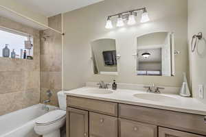 Full bathroom with tiled shower / bath combo, vanity, and toilet