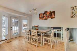 Dining area with lofted ceiling, a wealth of natural light, and light hardwood / wood-style flooring