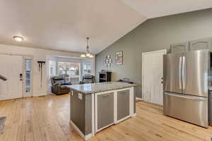 Kitchen with stainless steel refrigerator, decorative light fixtures, light hardwood / wood-style floors, and a notable chandelier