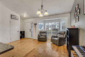 Living area featuring lofted ceiling, a notable chandelier, and light hardwood / wood-style flooring