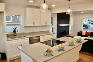 Kitchen featuring sink, a center island, dishwasher, pendant lighting, and white cabinets