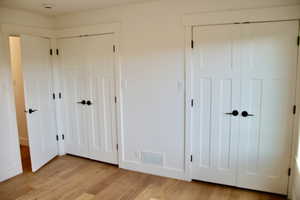 Unfurnished bedroom featuring two closets and light hardwood / wood-style flooring