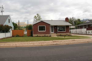 View of front of property featuring brick siding, a chimney, and roof with shingles