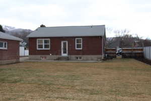 Rear view of property with a mountain view and a lawn