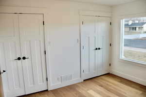 Unfurnished bedroom with two closets and light hardwood / wood-style flooring